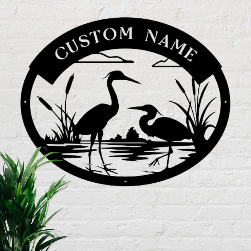 Black oval shaped sign with two herons and bulrushes. Custom name at top of sign.