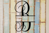 Decorative split letter monogram 'B' on a textured wooden background with pastel colors.