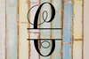 Decorative split letter monogram "C" on a wooden background with a rustic feel