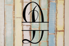 Decorative split letter monogram 'D' on a textured wooden background with pastel colors.