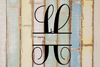 Decorative split letter monogram 'H' on a wooden background with a rustic finish.