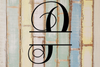 Decorative split letter monogram 'P' on a rustic wooden background with vertical planks.