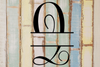 Decorative split letter monogram 'Q' on a wooden background with vertical stripes in various colors.
