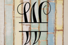 Decorative split letter monogram "W" on a wooden background with a rustic feel