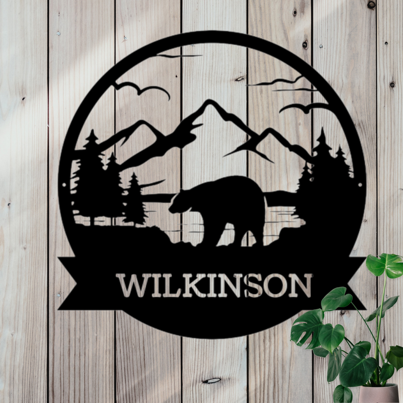 Round black metal sign with a bear, mountains and trees. Custom name at bottom.
