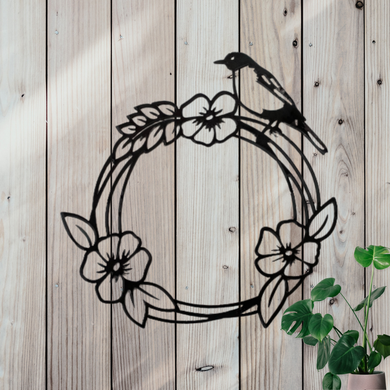 Black metal wreath with a bird and flowers that hangs on wall.