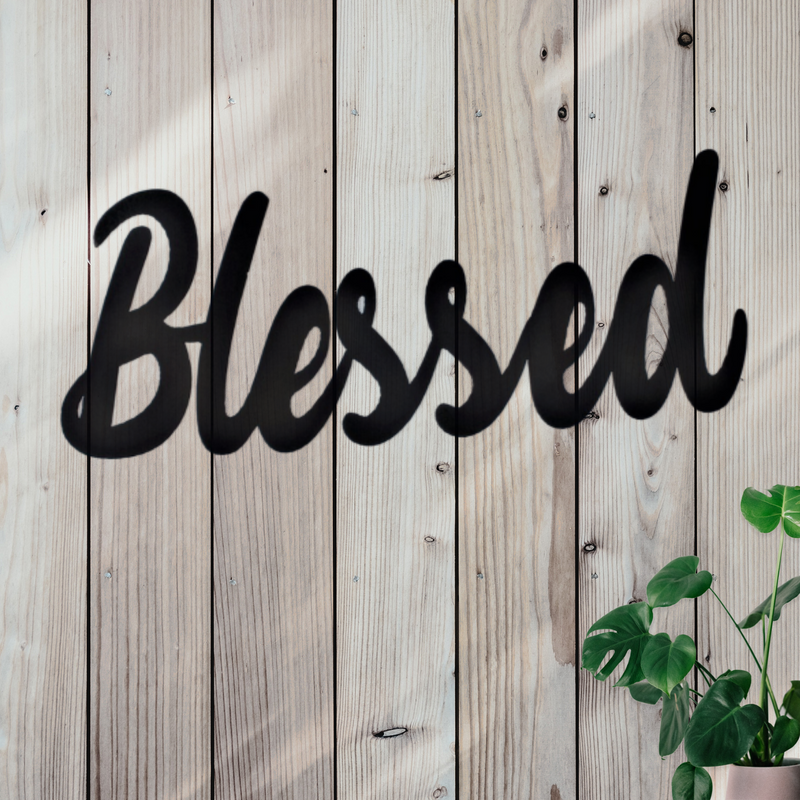 Metal sign with the word Blessed in cursive writing. 