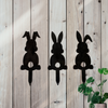 Three black metal garden stakes of bunny silhouettes. One rabbit with floppy ears,  one with straight ears and one with one floppy ear and one straight ear. All have a cut out fluffy tail.